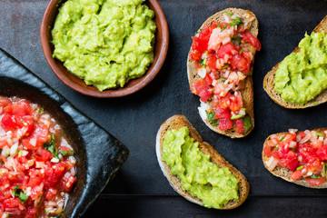Traditional mexican latinamerican sauce Guacamole, tomato sauce (Salsa), Avocado sandwiches and tomato sandwiches on dark background