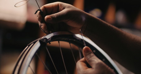 Hands of craftsperson repairing spokes on a bicycle wheel - Powered by Adobe