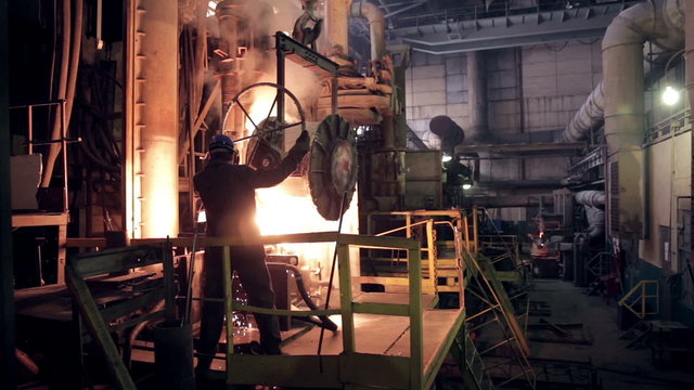 Worker on steel plant operates with  molten metal. HD.