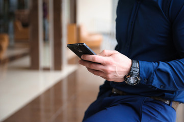 businessman looking through the phone by the window