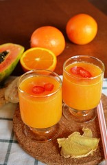 Glass of orange and papaya smoothie on a wooden table. Closeup.