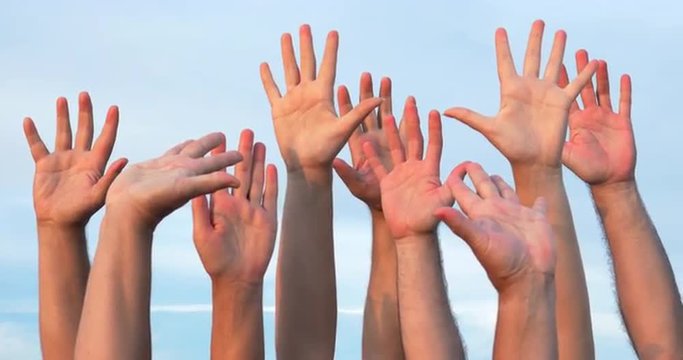 Several people raising hands up in the air against of blue sky