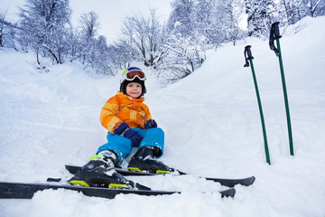 Fototapeta na wymiar Little skier boy rest in snow wear ski outfit