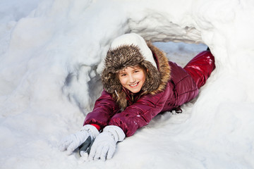 Fototapeta na wymiar Girl in winter clothes playing at a snow hole