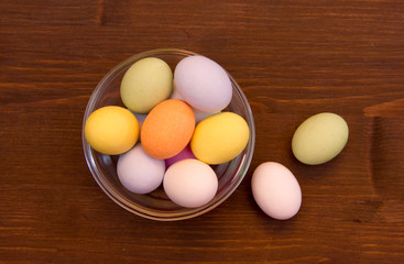 Colored eggs on a bowl on wooden table top views