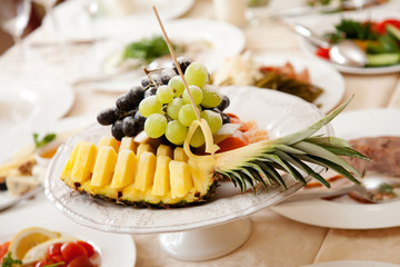 Fruit plate on restaurant table: pineapple, grape, orange