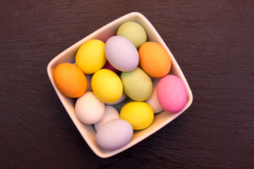 Colored eggs inside bowl on slate top top views