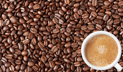 Close-up of coffee beans background and white coffee cup