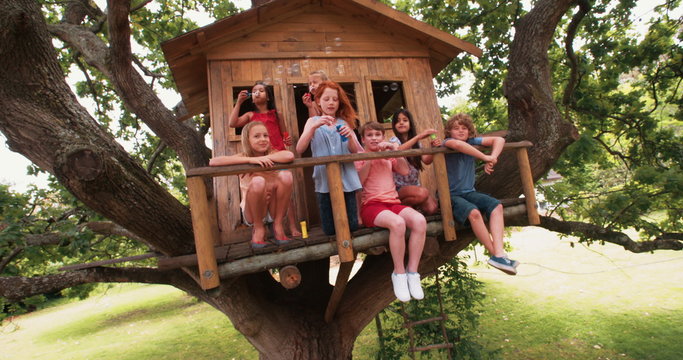 Children blowing bubbles on the porch of a wooden treehouse