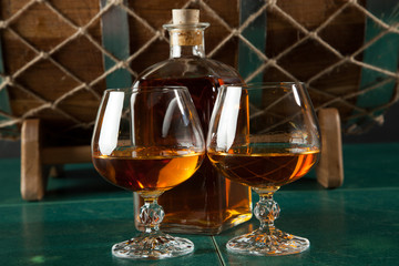 Two glasses of brandy and bottle on a green table top - 106428245