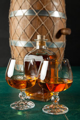 Two glasses of brandy and bottle on a green table top