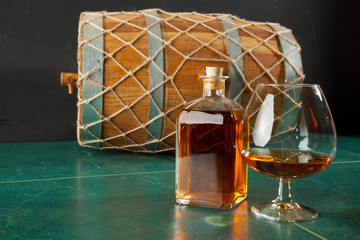 Glass of brandy and bottle on a green table top