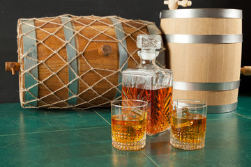 Two whiskey glasses and a decanter on a green table top
