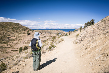 Backpacker exploring Inca trails on the Island of the Sun, Titicaca Lake, scenic travel destination in Bolivia. Cross processed with vintage tones and film effect.