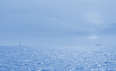 Boat silhouette over sea and blue sky, blue tone