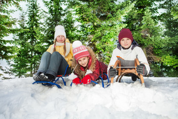 Boy and girls sitting on their sledge at the hills