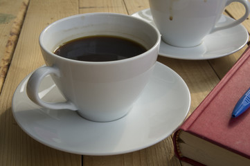 cup of coffee morning with red book blue pen