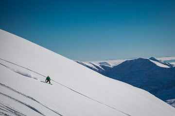 Male skier skiing in fresh snow on ski slope on a sunny winter day at the ski resort in Georgia