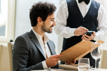 Man with menu in a restaurant making order
