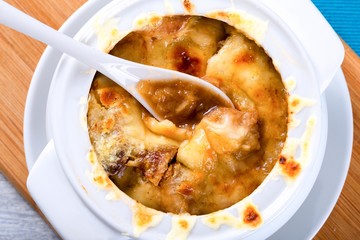 french onion gratin soup in a white pot, close-up