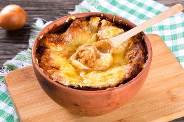 french onion gratin soup in a white pot, close-up