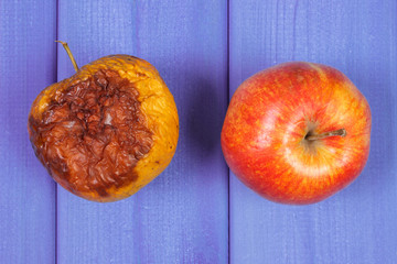 Old wrinkled and fresh apples on purple boards