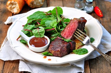 Medium steak with salad and barbecue sauce