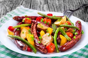Grilled sausage with garlic, potato, cherry tomatoes, green beans, top-view