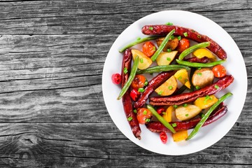 Grilled sausage with garlic, potato, cherry tomatoes, green beans, top-view