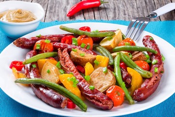 Grilled sausage with garlic, potato, cherry tomatoes, green beans, top-view