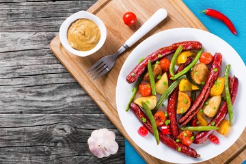 Grilled sausage with garlic, potato, cherry tomatoes, green beans, top-view