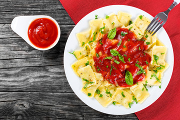  ravioli with tomato sauce and basil leaves, top view