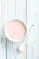 Strawberry yogurt in bowl on a blue wooden table