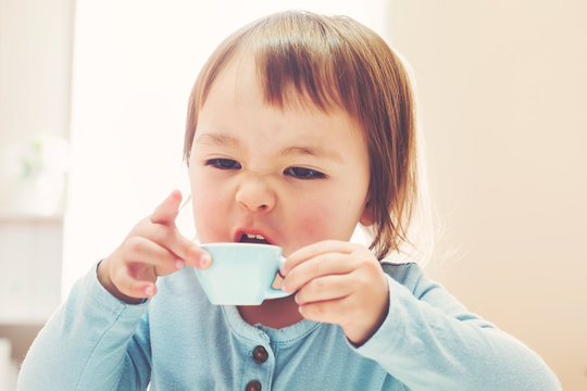 Happy toddler girl drinking from a teacup