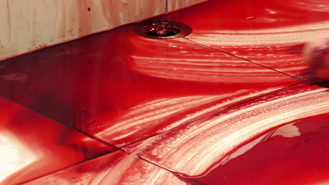 Detailed view of animal intestines handled by hand in a slaughterhouse,zooming out from close up of organs to the man performing this task meticulously.