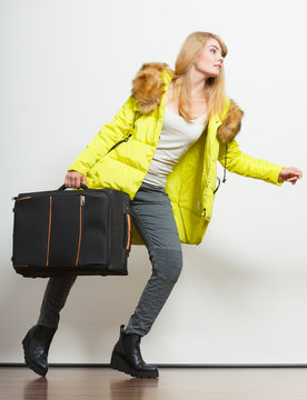 Young woman in warm jacket with suitcase.