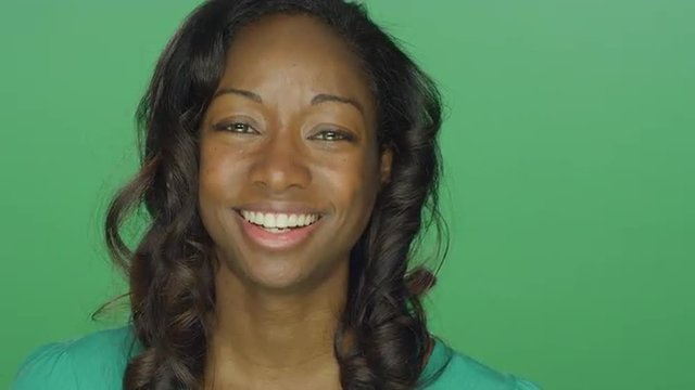 Beautiful African American woman smiling and laughing, on a green screen studio background