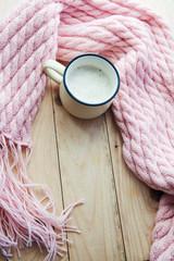 top view image of a pink cosy knitted scarf with a Cup of coffee on wooden table