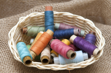 Fototapeta na wymiar Coils with colorful threads in a wicker basket