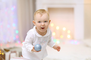 Fototapeta na wymiar Funny baby girl with Christmas toy near Christmas tree on bright background