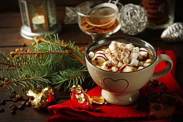 Mug of hot chocolate with marshmallows, fir tree branch on wooden background