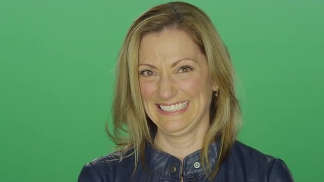 Beautiful middle aged woman smiling and laughing, on a green screen studio background