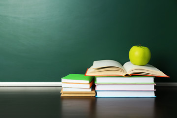 School books on desk near chalkboard