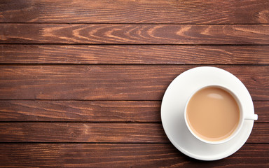 Porcelain cup of tea with milk on wooden background
