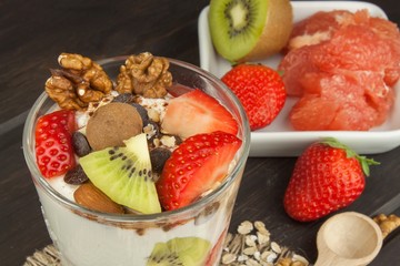 Preparing healthy breakfast for kids. Yogurt with oatmeal, fruit, nuts and chocolate. Oatmeal for breakfast. Preparing diet meals. A healthy diet for athletes.
