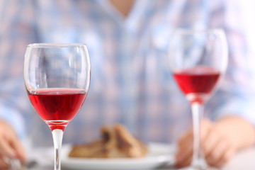 Dinner with glasses of wine at table on light blurred background