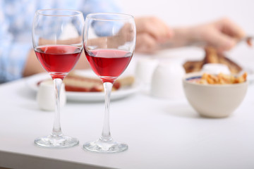 Dinner with glasses of wine on light blurred background