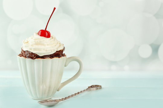 Chocolate mug cake with cream and cherry on a table