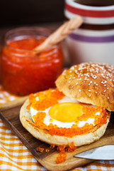Fried egg with red caviar on a bun