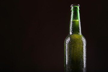 Green glass bottle of beer on dark  background, close up